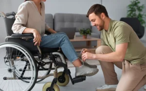Accompagnant éducatif et social aidant une personne en situation de handicap à lacer ses chaussures