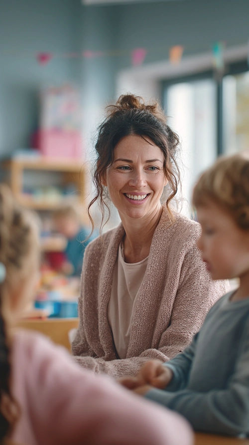 Accompagnante éducative petite enfance souriante en crèche accompagnant des enfants lors d’une activité éducative