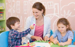 Intervenante éducative petite enfance accompagnant deux jeunes enfants lors d’une activité créative