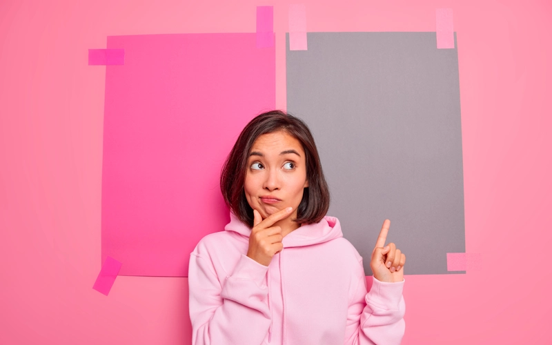 Femme hésitante sur fond rose