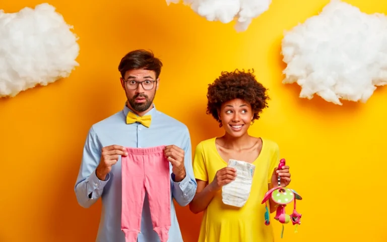 Père et mère au foyer posant avec des vêtements, couche et jouet pour bébé
