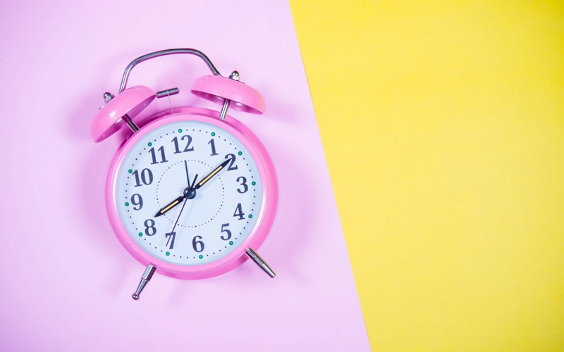 Horloge rose sur fond jaune et rose